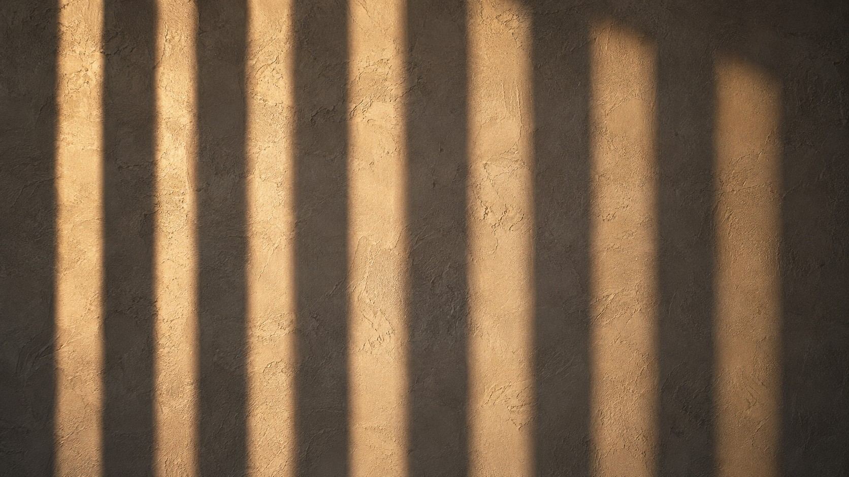 Franjas de luz y sombra sobre un muro de aplanado cálido
